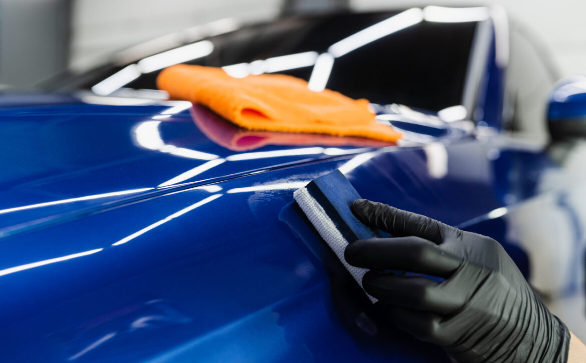 Process of applying ceramic protective coat on body car using sponge in detailing auto service. Car service worker apply ceramic coating to protect the car body from scratches.