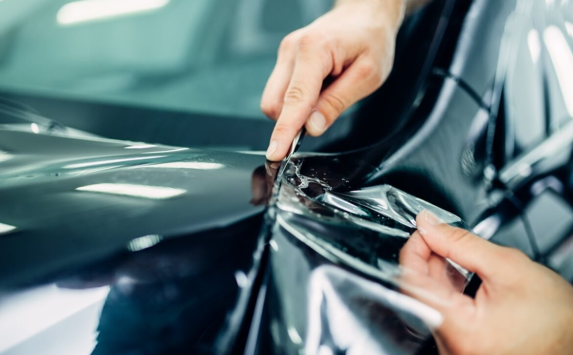 Worker hands installs car paint protection film